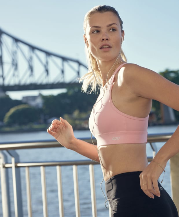 two models wearing sports bras and leggings, with one model clipping the back of the sports bra up